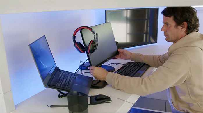 Una persona frente al notebook gamer, teclado, mouse, audífonos y monitores en el camarote gamer