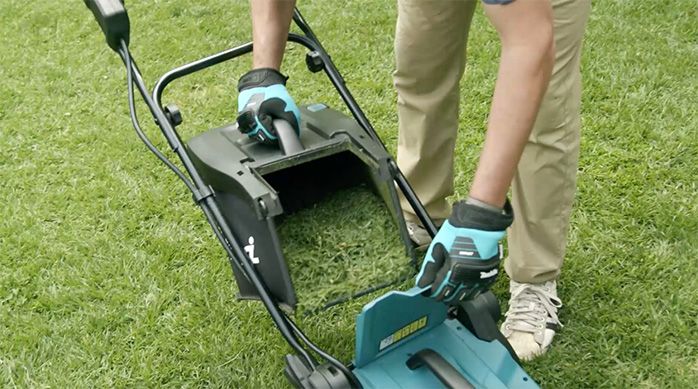 Una persona retira el depósito lleno de pasto de la cortadora para césped Makita