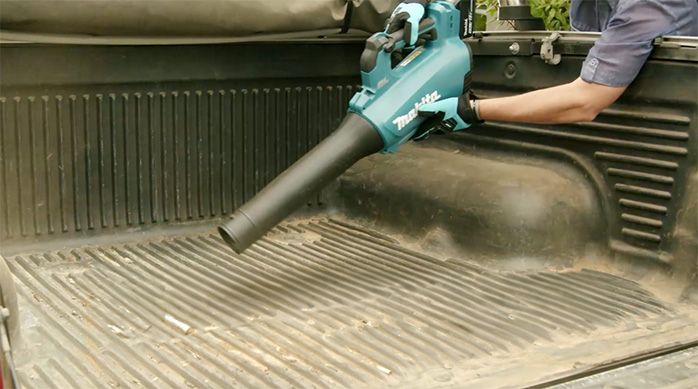 Una persona usa la sopladora Makita para remover el polvo de una camioneta