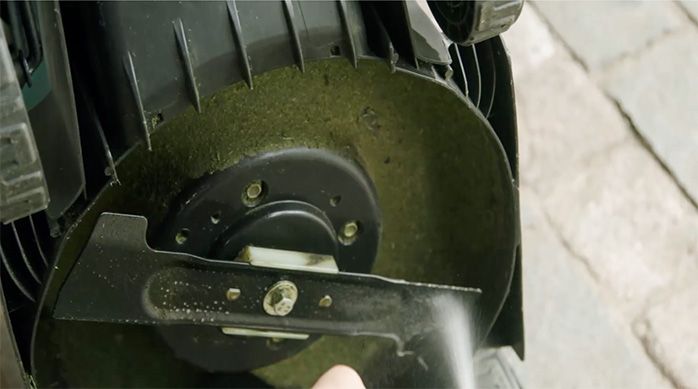 Una persona aplica lubricante a la hoja de corte de la cortadora de césped Makita