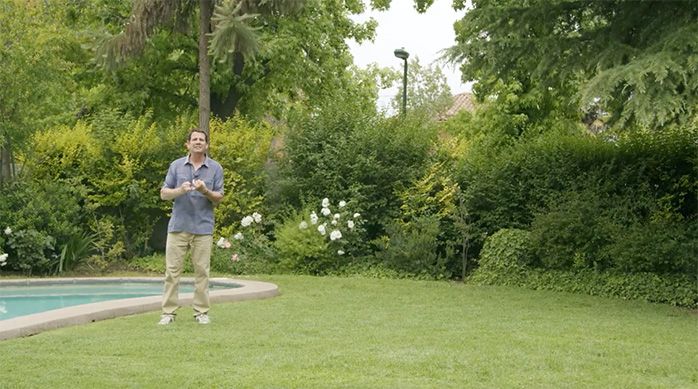 Una persona en un jardín con el césped verde recién cortado