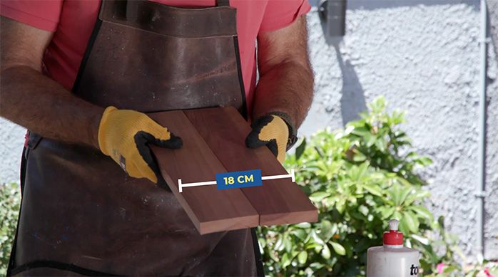Una persona presenta dos tablas para mostrar la base de las repisas del organizador para baño