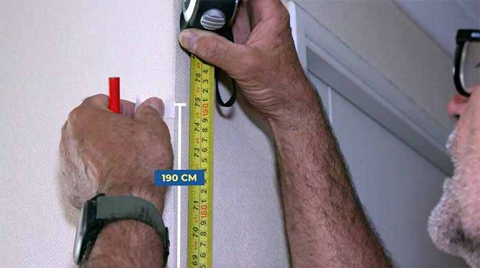 Una persona mide 190 cm de alto en una pared con una huincha de medir