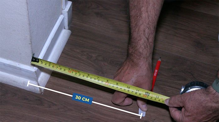 Una persona mide 30 cm desde la pared y marca el lugar con cinta de enmascarar