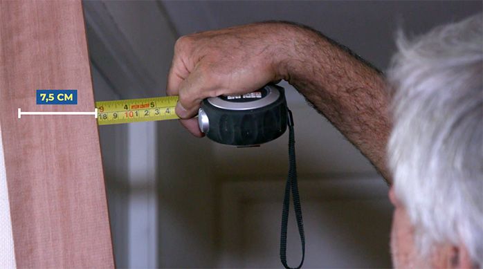 Una persona mide 7,5 cm en la tabla de madera con una huincha de medir