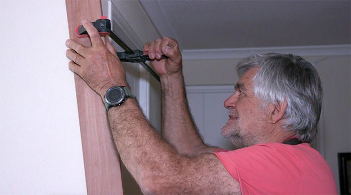 Una persona aprieta la tabla de madera en la pared con una prensa manual