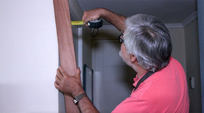 Una persona mide la parte superior de la tabla de madera con una huincha de medir