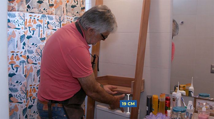 Una persona presenta la primera repisa del organizador para baño a 19 cm desde el escusado