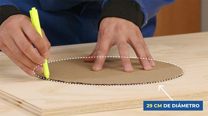Una persona dibuja un círculo de 29 cm de diámetro para hacer la entrada de la casa para gato