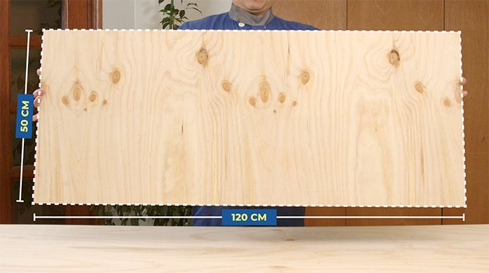 Una persona muestra una plancha de terciado de 50 x 120 cm