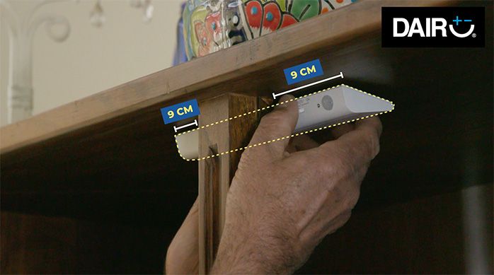 Una persona presenta la luminaria led en el interior del mueble de vitrina
