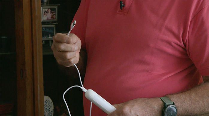 Una persona muestra el cable usb para cargar la luminaria led tubular portátil