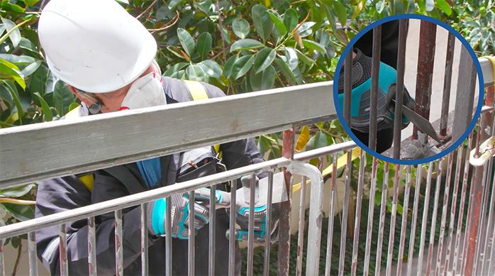Una persona retira la pintura vieja de la baranda metálica con una espátula metálica