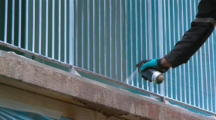 Una persona pinta la baranda de terraza con pintura anticorrosiva en spray