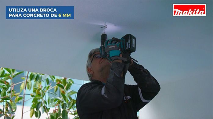 Una persona perfora con un taladro percutor el cielo de la terraza o balcón