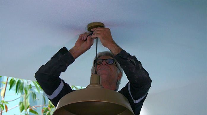 Una persona instala una lámpara en el cielo de la terraza o balcón