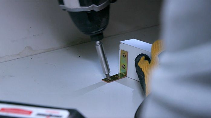 Una persona atornilla la escuadra para fijar el vertical al mueble