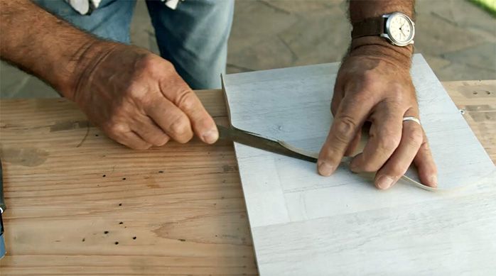 una persona corta el exceso de tapacanto con un cuchillo cartonero