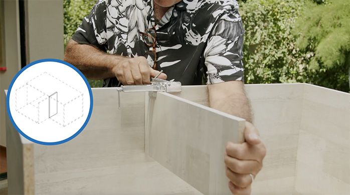 Una persona presenta el vertical del mueble arenero y lo afirma con una prensa