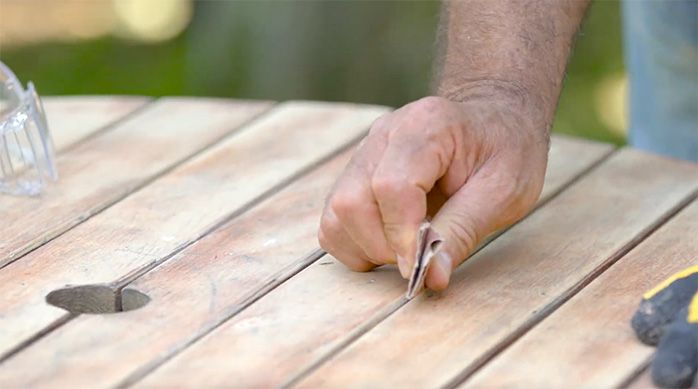 una persona lija la mesa de madera manualmente