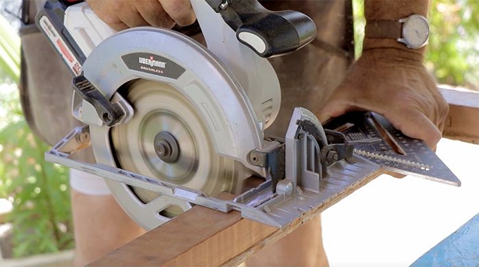 un hombre corta un marco de madera con una sierra circular