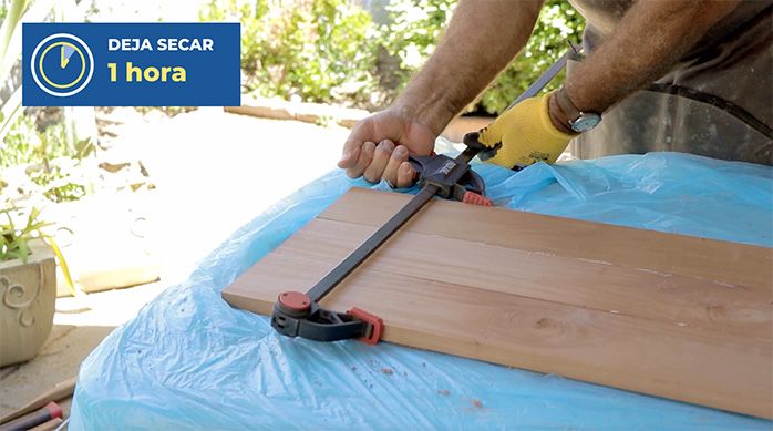 un hombre aprieta 3 trozos de madera con unas prensas