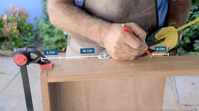 un hombre marca las perforaciones en la parte inferior del escritorio home office