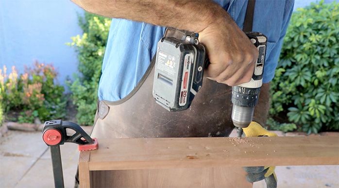 un hombre perfora la estructura de madera del escritorio home office