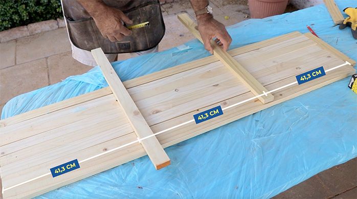 un hombre pone varios trozos de madera para armar una rejilla para el escritorio home office