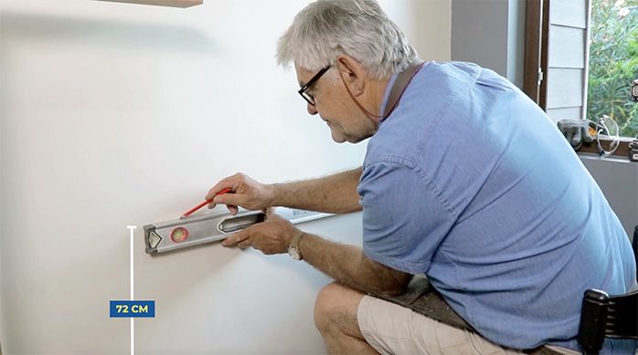 un hombre mide la altura deseada para el escritorio home office en la pared