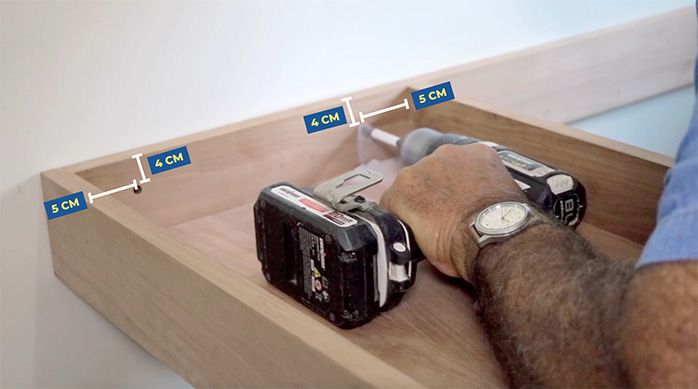 un hombre fija el escritorio home office a un muro