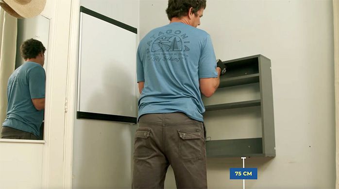 una persona presenta el escritorio plegable a la altura adecuada de 75 cm en la pared