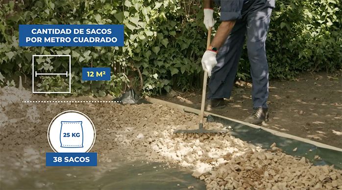 un hombre distribuye sacos de gravilla por todo el piso del patio.