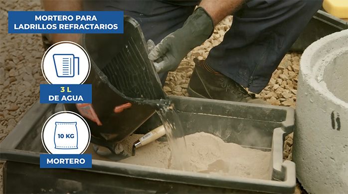 un hombre hace la mezcla del mortero para pegar los ladrillos refractarios en una batea.