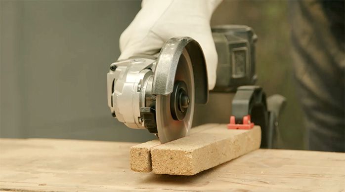 una persona con guantes de seguridad corta un ladrillo refractario con un esmeril angular.