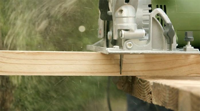 una persona corta un trozo de madera con una sierra circular.