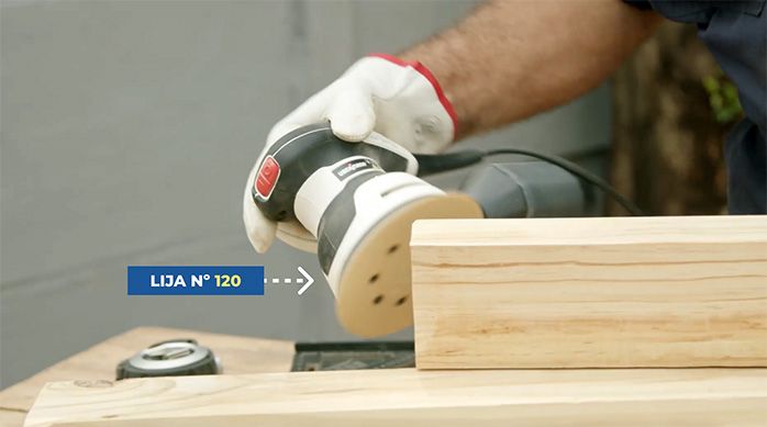 una persona usa una lijadora roto orbital con lija n.° 120 para suavizar un trozo de madera.