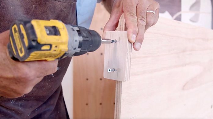 un hombre fija un trozo pequeño de madera en el separador de ambientes de madera