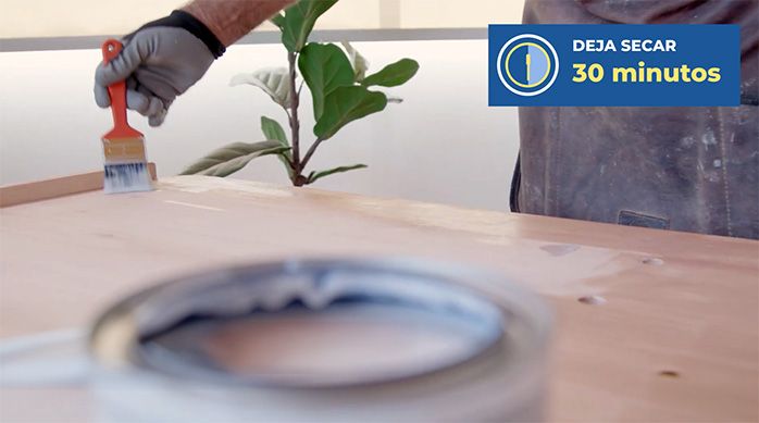 un hombre aplica barniz con una brocha en el separador de ambientes plegable