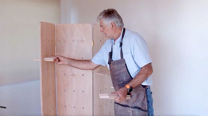 un hombre presenta las repisas en el separador de ambientes de madera