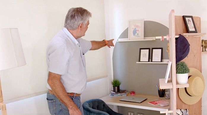 un hombre muestra la repisa del home office delimitado por un separador de ambientes de madera