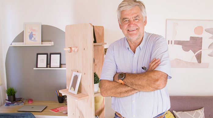 un hombre con los brazos cruzados feliz al lado de un separador de ambientes plegable