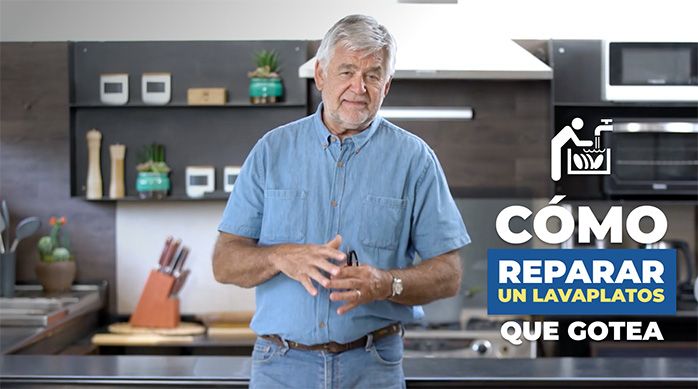 un hombre en una cocina enseñando a cómo reparar un sifón de un lavaplatos que gotea
