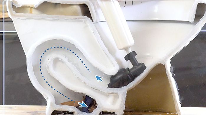 un inodoro con un destapador de presión en la salida de agua para destapar el wc