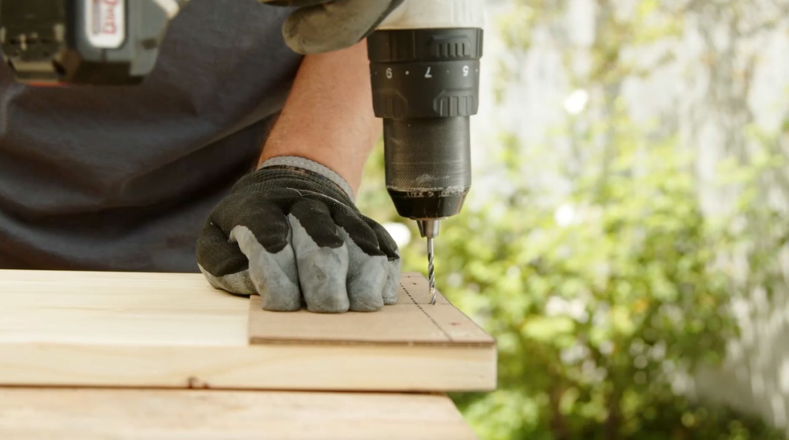 una persona perfora el borde de un trozo de madera laminada usando una plantilla