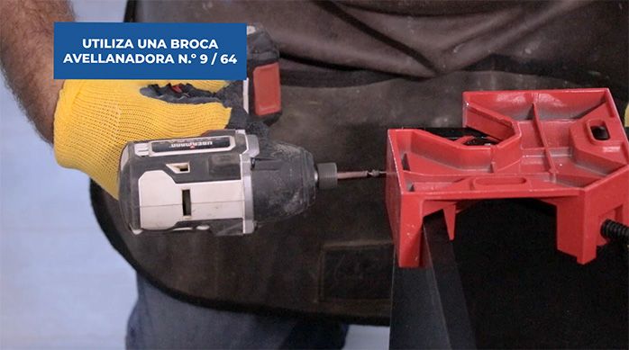 un hombre con guantes de trabajo fija la esquina del mueble gamer con tornillos