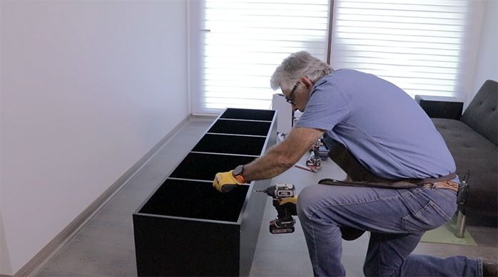 un hombre fija una repisa en el mueble gamer para consolas