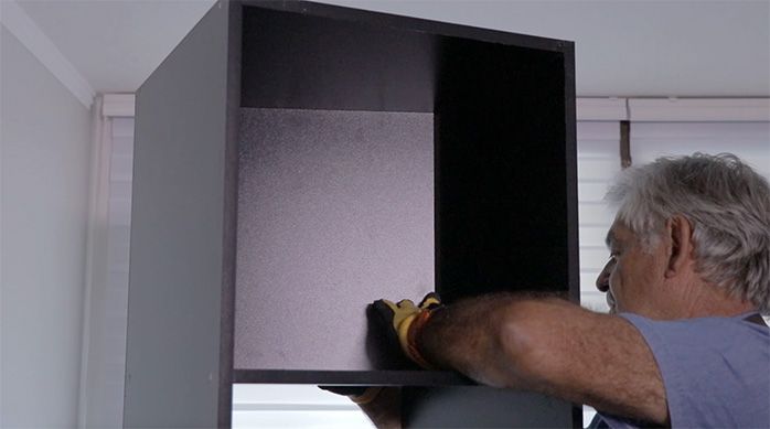 un hombre pone un fondo en el mueble gamer