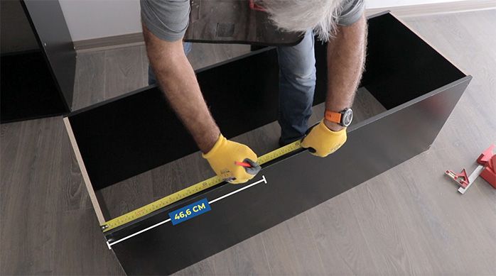 un hombre marca 46,6 cm en uno de los lados del cajón para el mueble gamer