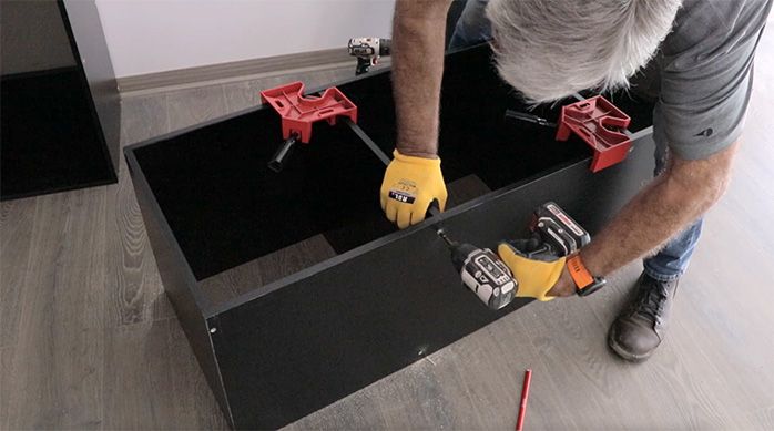 un hombre fija la división del mueble gamer horizontal con tornillos